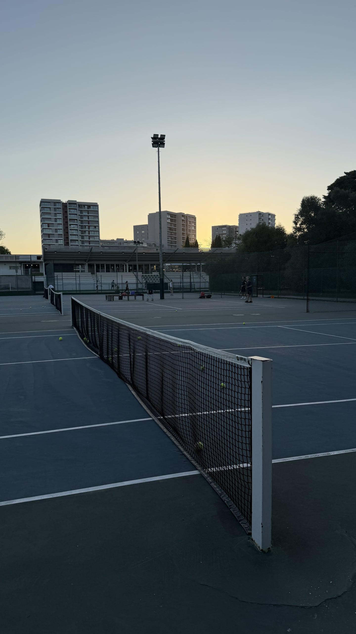 Court de tennis extérieur en dur et filet au Rackets Pro EUL au coucher du soleil